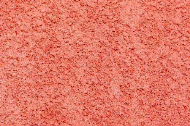 Close-up of a coral-colored textured plaster surface with a rough finish.