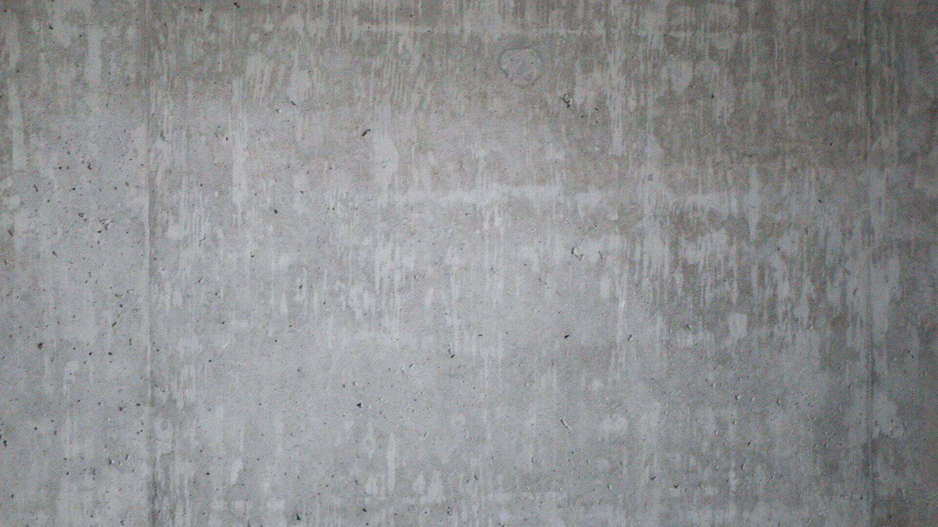 Close-up view of a plain concrete wall with rough texture and vertical lines.