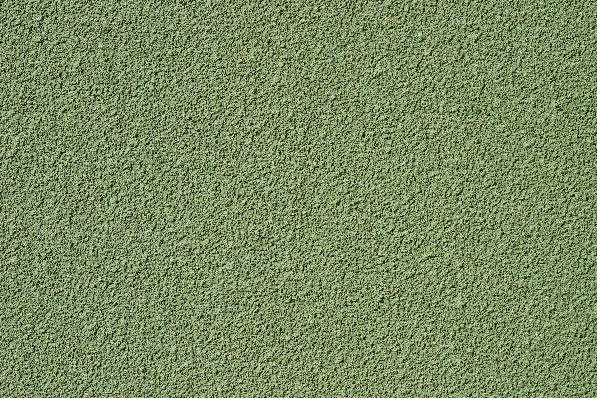 Close-up view of a green stucco wall with a rough texture, showing uniform surface details.