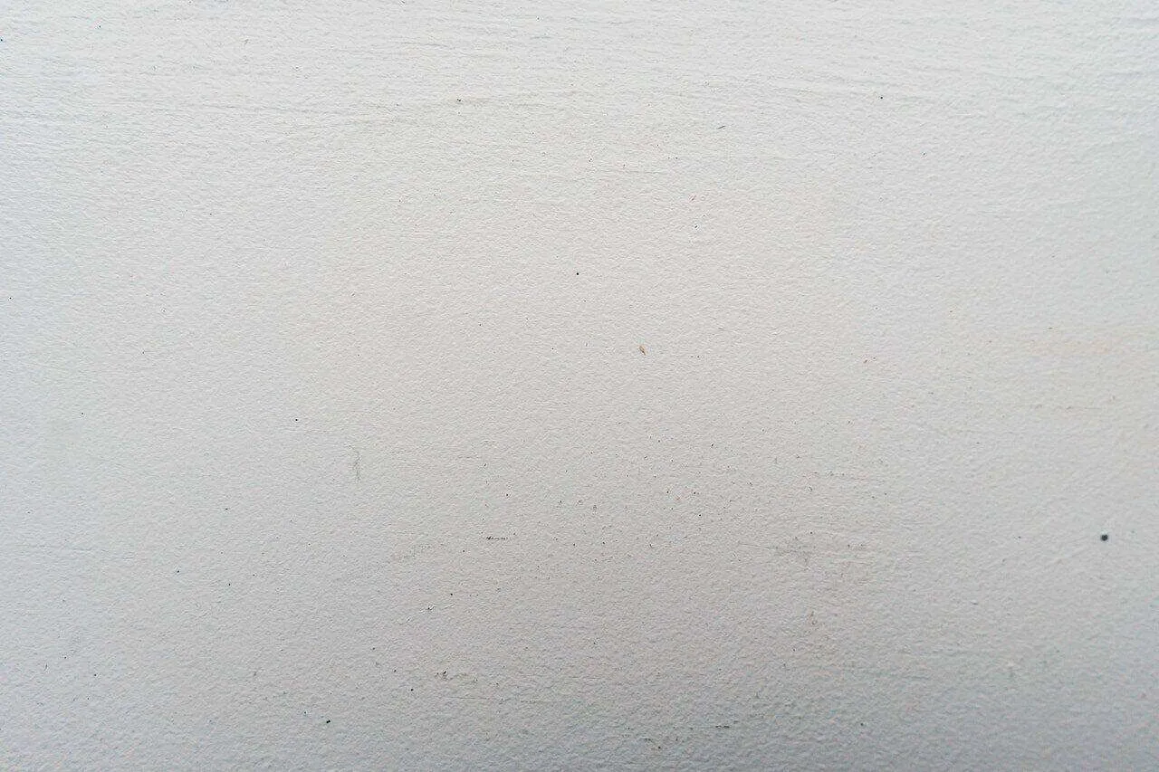 Close-up view of a smooth, light-colored plaster wall surface with minor imperfections.
