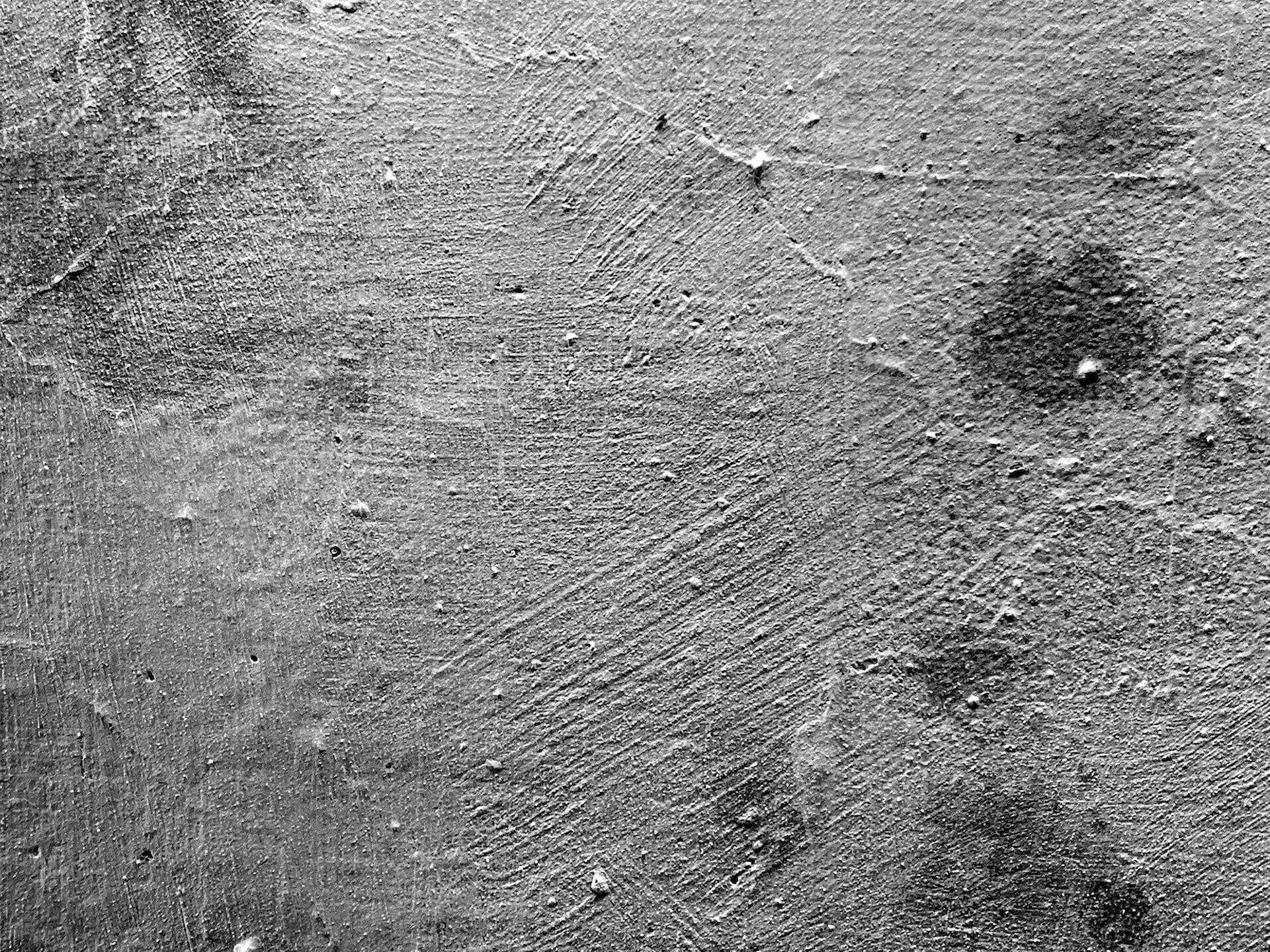Close-up of a textured plaster wall with rough patterns and dark spots.