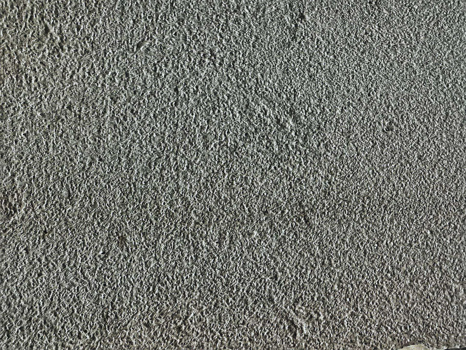 Close-up view of a textured stucco wall with a rough finish, showing detailed surface texture. — Ross area