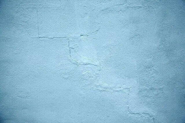 Close-up of a blue stucco wall with visible cracks and texture, indicating wear. — Kentfield area