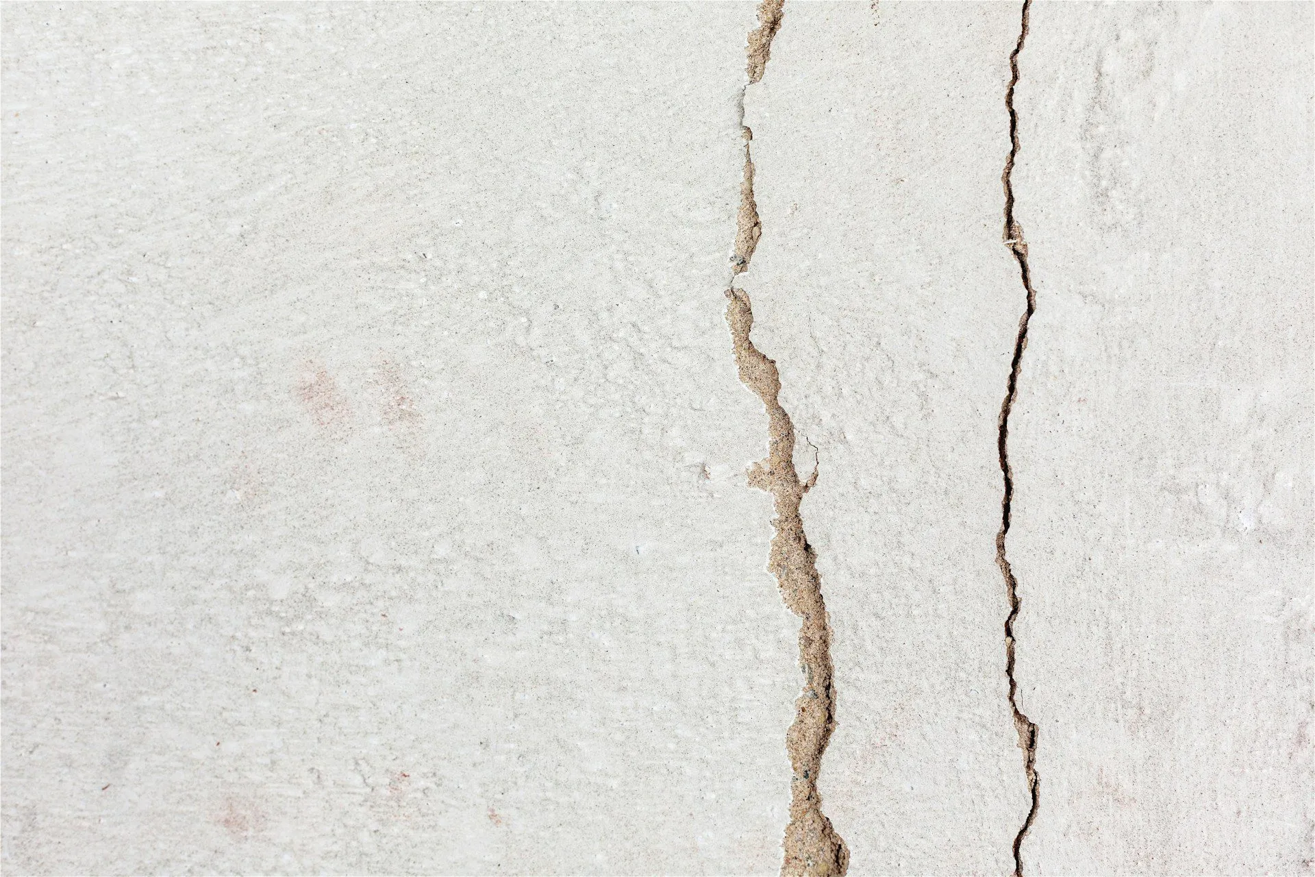 Close-up of a vertical crack in a plaster wall showing texture and depth.
