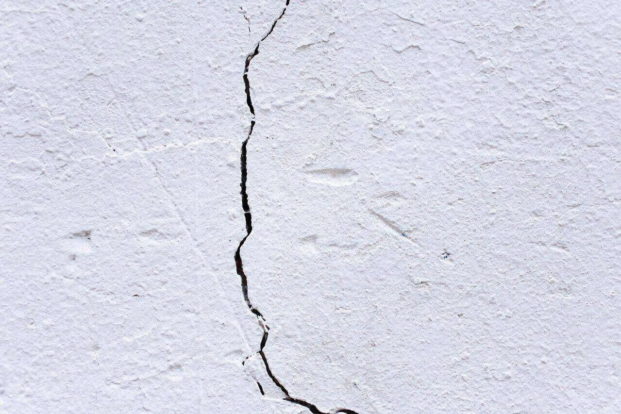 Close-up of a white plaster wall with a vertical crack.