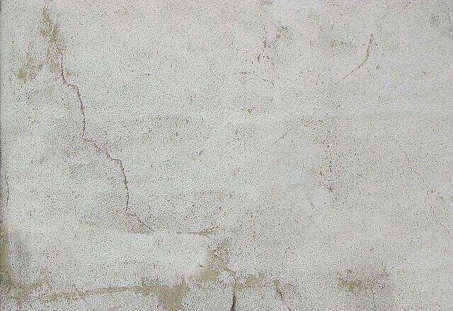 Close-up of a cracked plaster wall showing texture and discoloration.