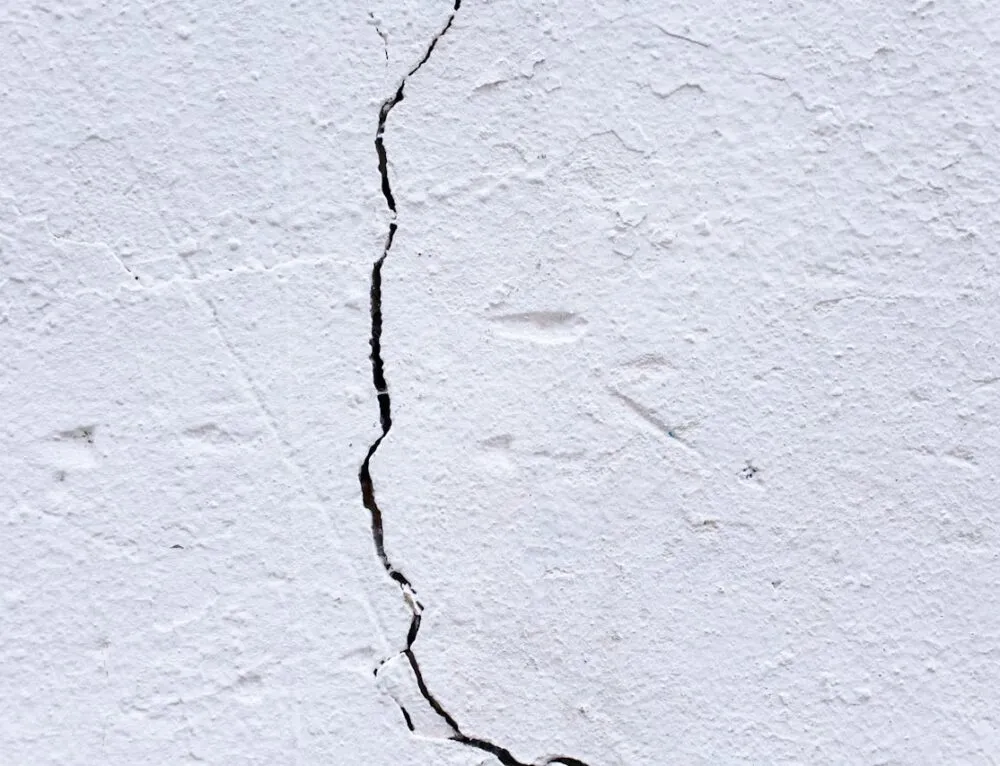 Close-up of a white stucco wall with a vertical crack, showing rough texture. — Hillsborough area