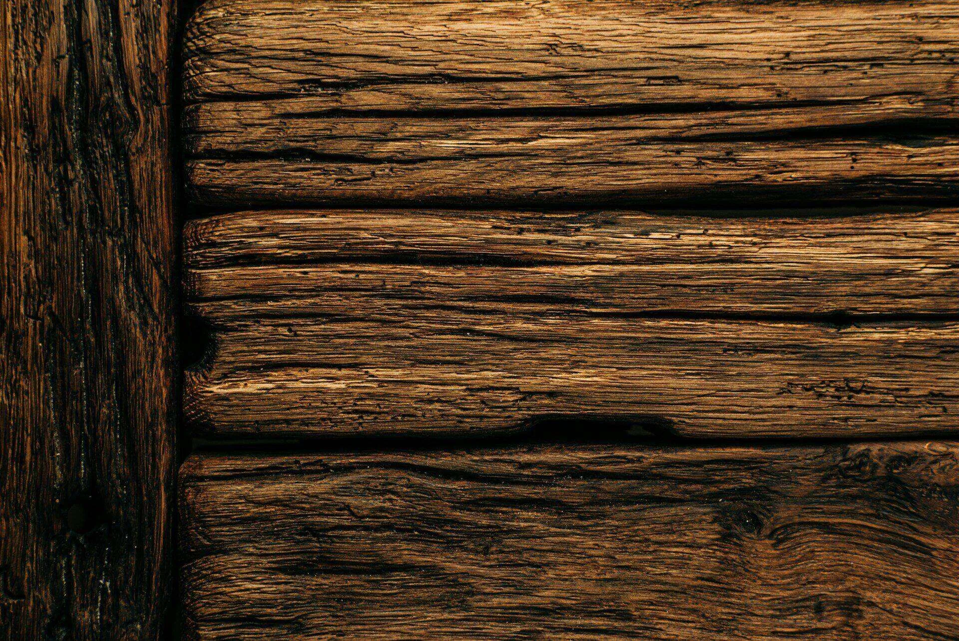 Close-up of wooden beams with visible dry rot, showing cracks and decay.