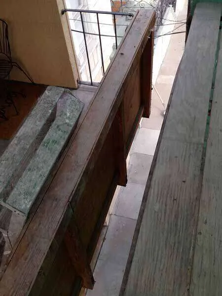 Wooden balcony with visible wear, showing potential dry rot issues.