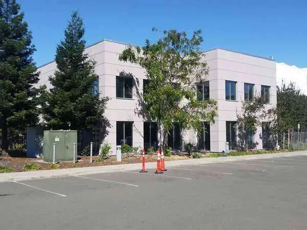 Two-story office building with EIFS cladding, large windows, and surrounding trees. — Ross area