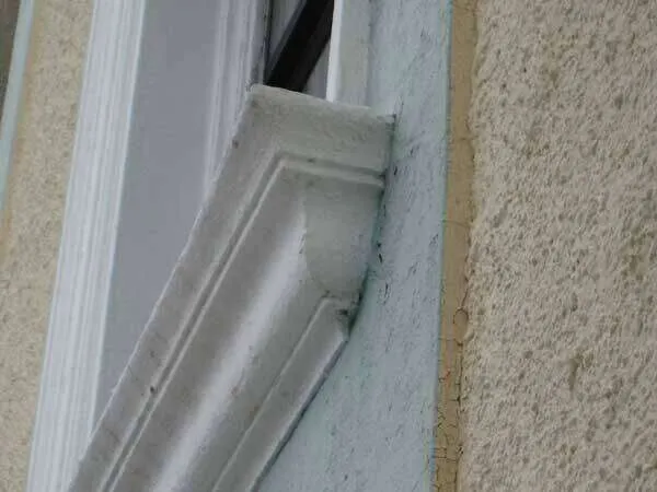 Close-up of EIFS detailing around a window with textured finish and trim.
