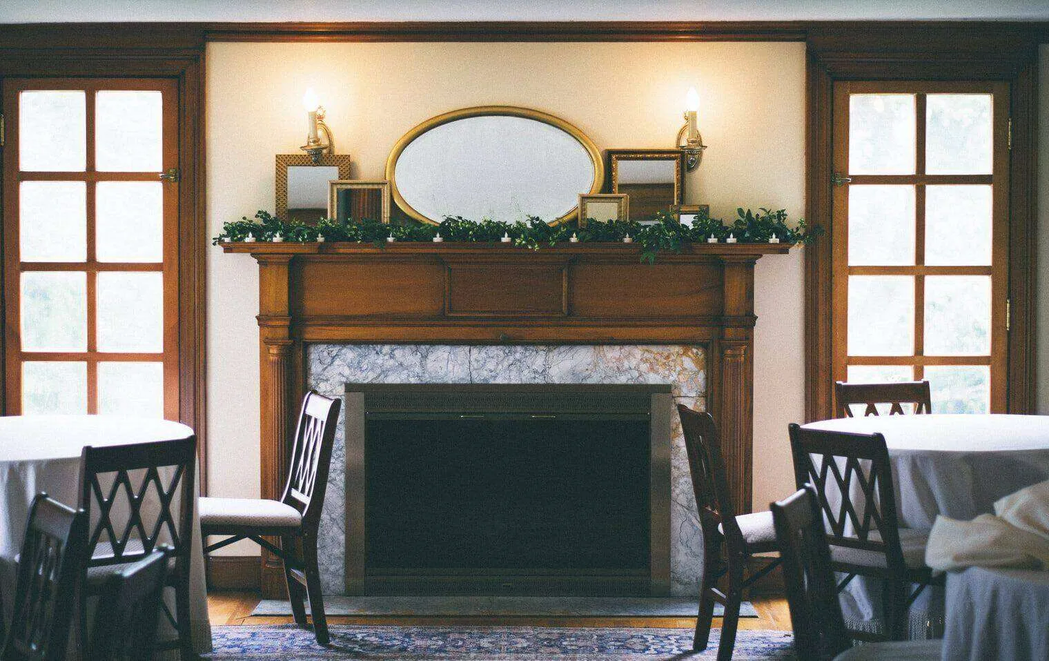 Traditional living room with marble fireplace, wooden mantel, and decorative mirrors.