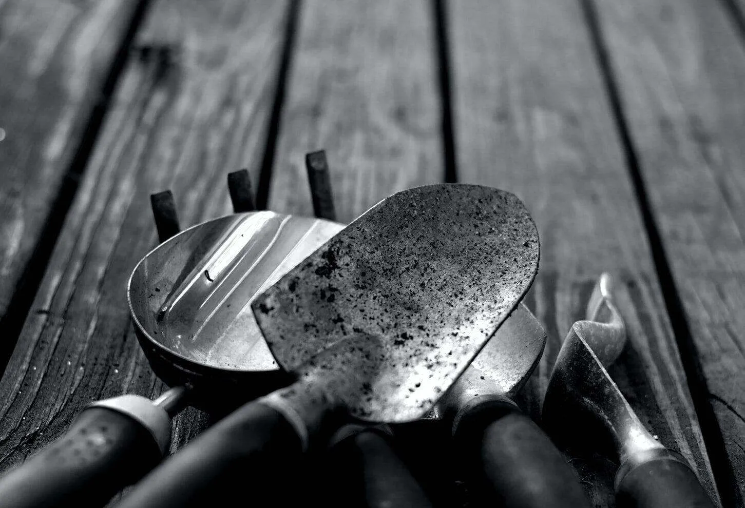 Close-up of plastering tools including trowels and a float on a wooden surface.
