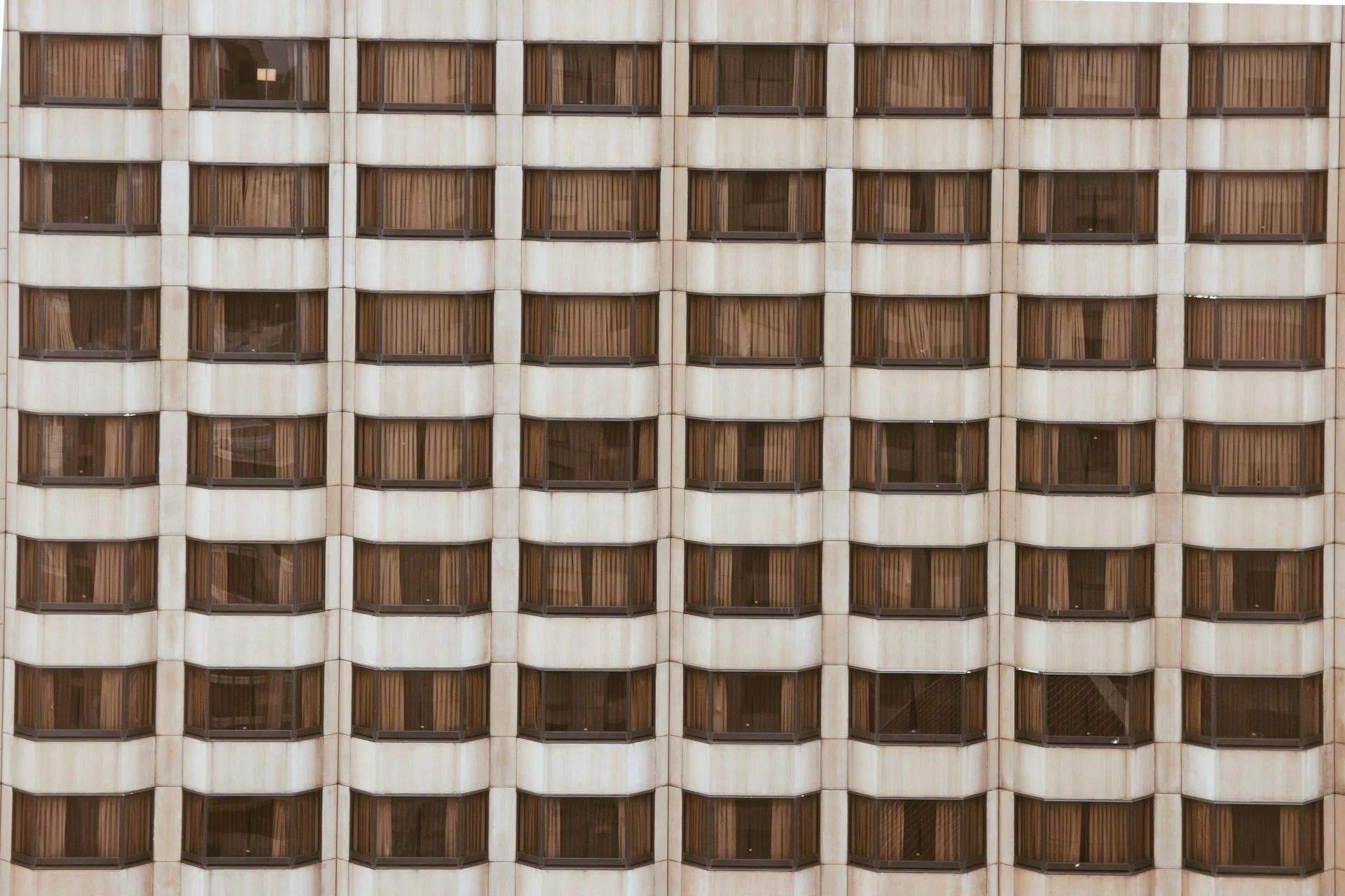 Facade of a high-rise building with a grid of windows and beige panels.