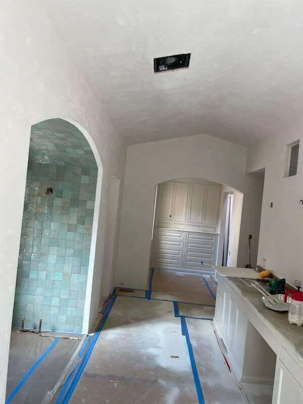 Interior room with plastered walls, tiled archway, and floor covered for renovation.