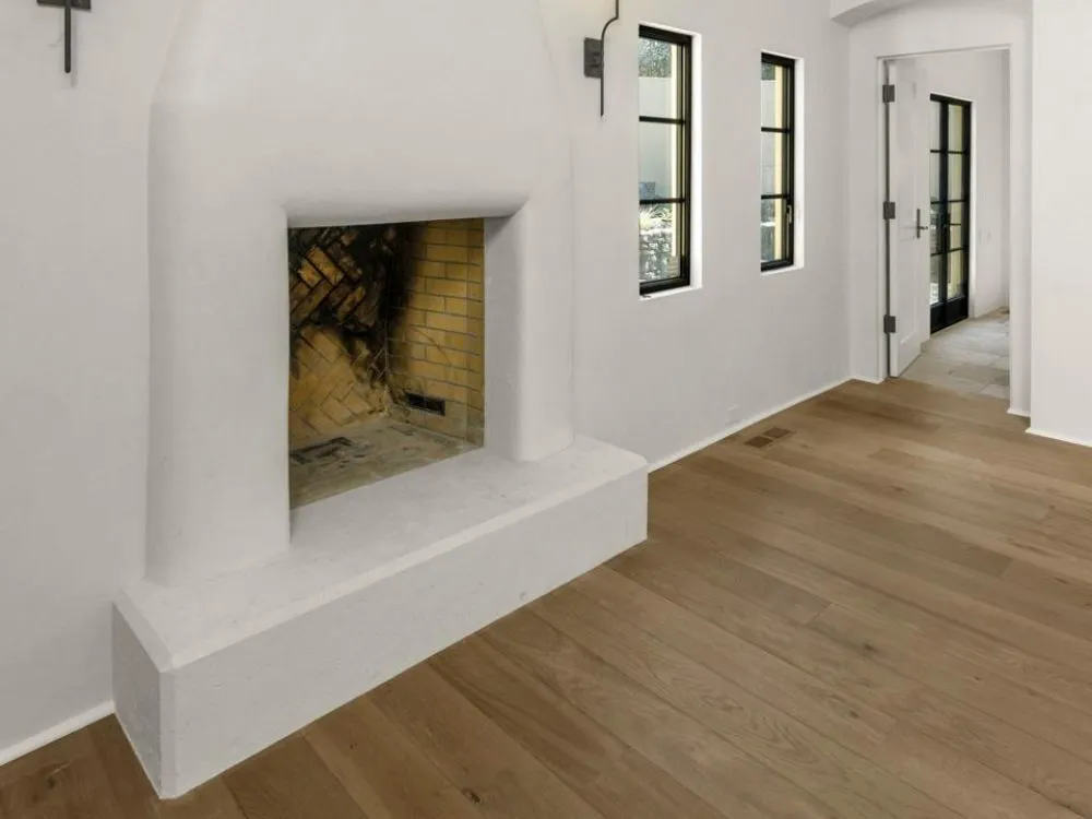 Interior view featuring a white stucco fireplace, wooden floors, and narrow black-framed windows. — work near St. Helena