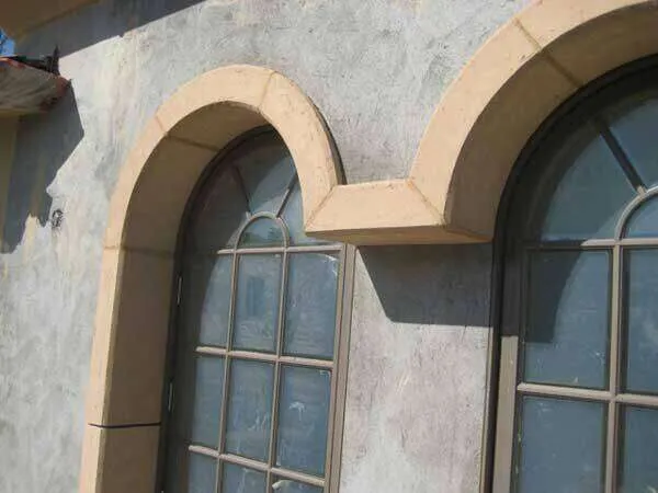 Exterior view of arched windows with lymestone foam trim and textured wall finish.