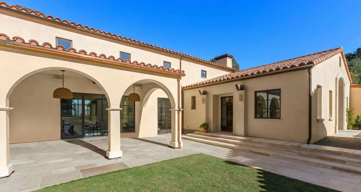 Mediterranean-style commercial building with stucco walls, arched walkways, and terracotta roof tiles.