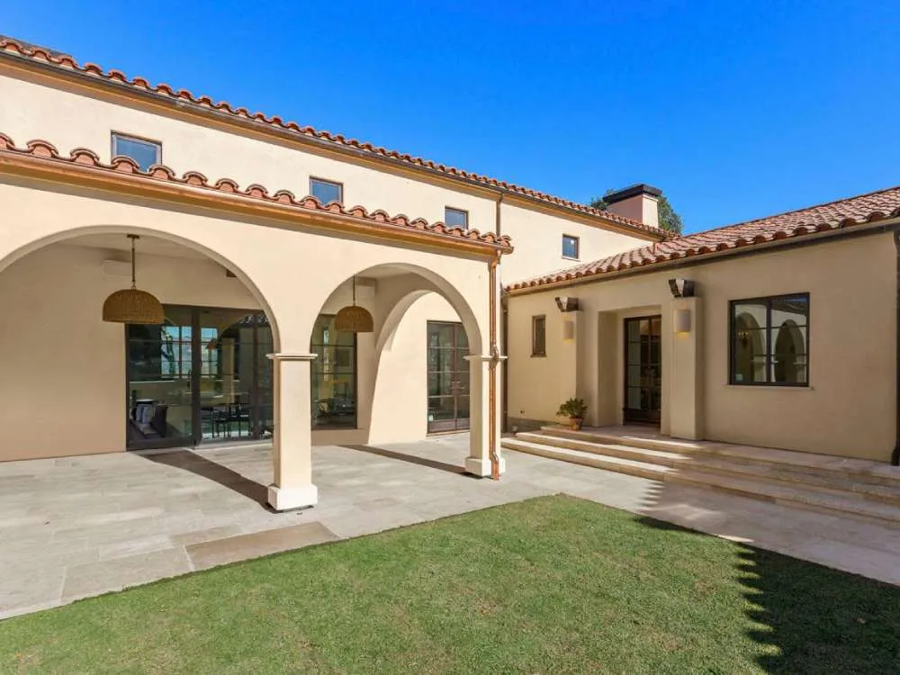 Mediterranean-style courtyard with stucco walls, arched columns, and tiled roof under a clear blue sky. — Alameda area