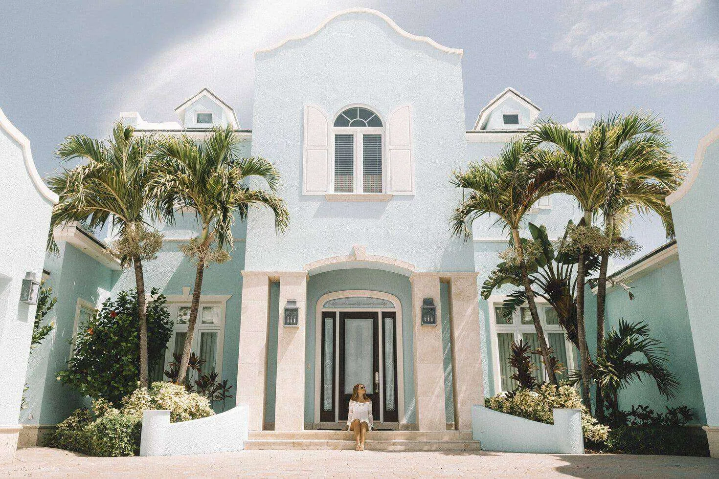 Pastel blue Mediterranean house with arched windows and palm trees in the front yard. — Tiburon area