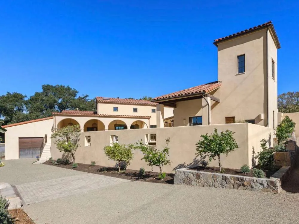 Mediterranean-style building with stucco walls, red-tiled roof, and landscaped surroundings.