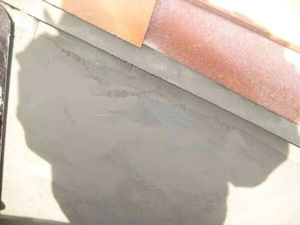 Close-up of a wall with mesh embedded in plaster, showing construction detail.