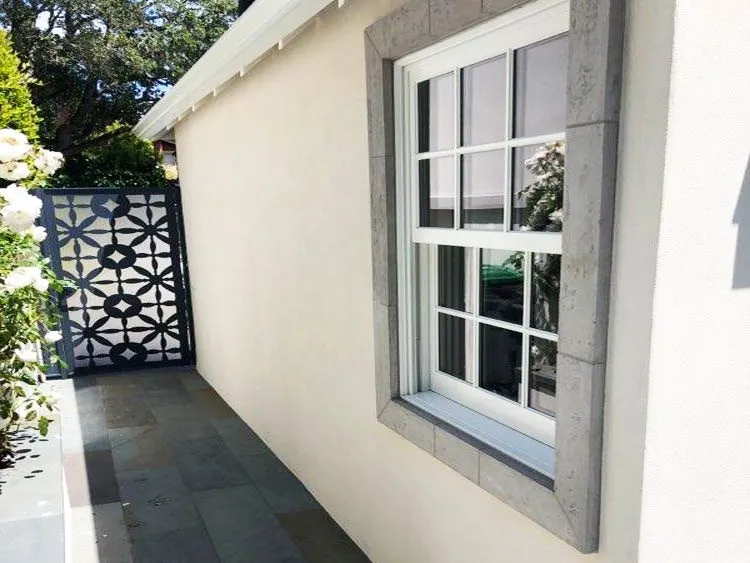 Exterior of a Mill Valley home with smooth stucco wall, stone-trimmed window, and decorative gate.