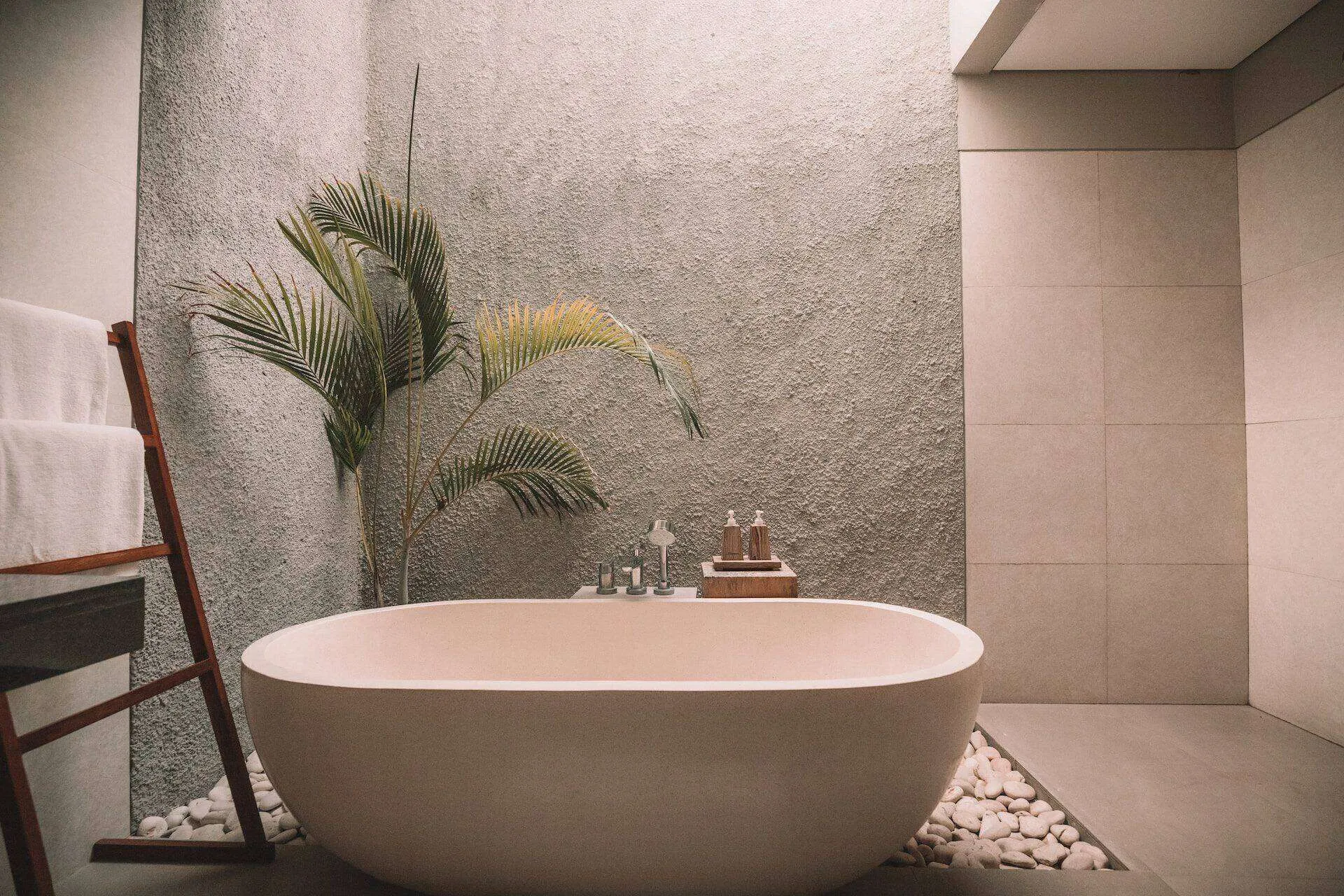 Modern bathroom with a freestanding tub, textured wall, and potted plant.