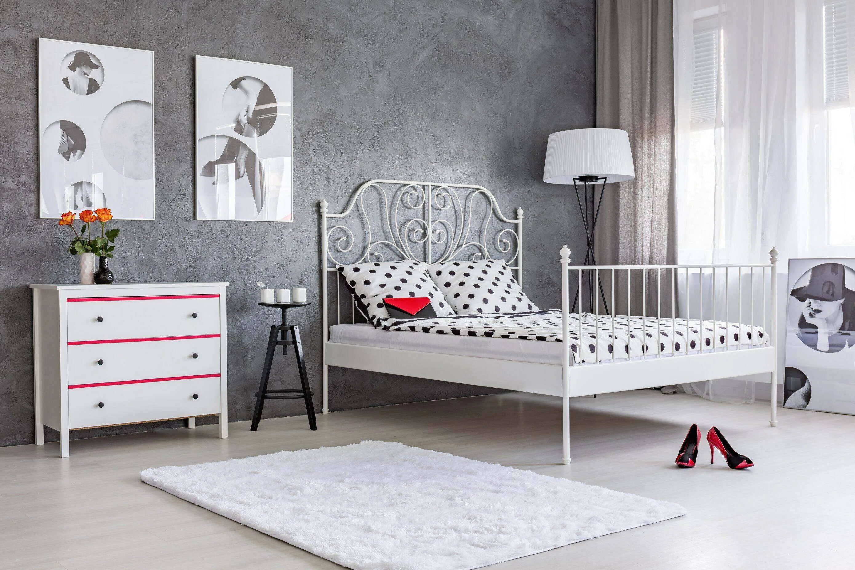 Bedroom with grey stucco wall, white metal bed, polka dot bedding, and minimalist decor.