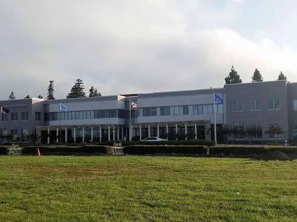 Large commercial building with stucco exterior and flags, Bay Area. — Kensington area