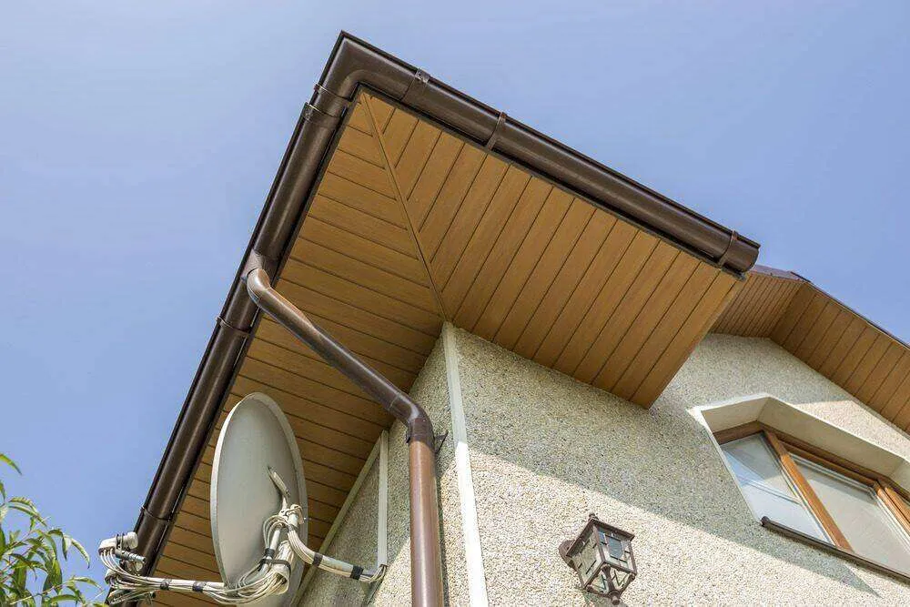 Bottom view of modern house roof eaves with gutter and satellite dish, textured wall finish. — Tiburon area