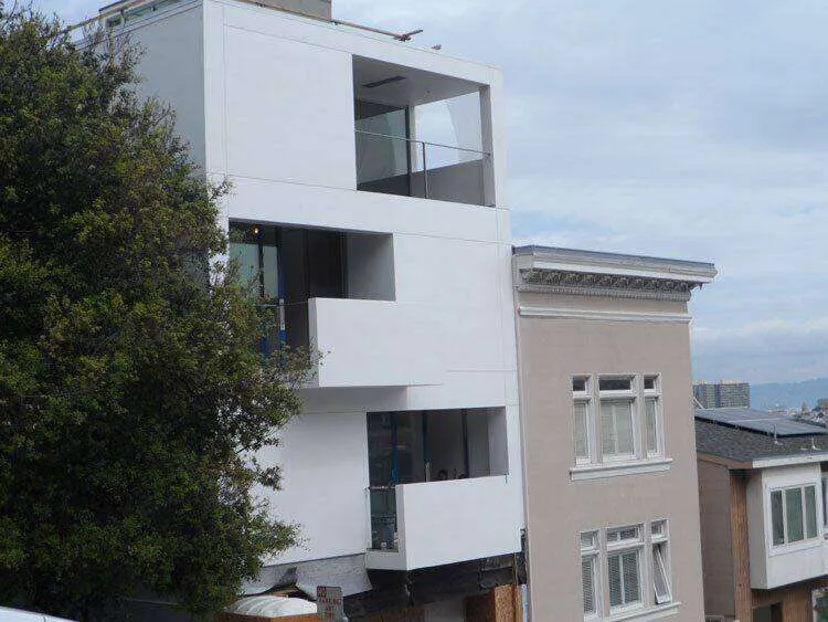 Modern multi-story building with smooth white exterior and large glass windows in an urban setting. — El Cerrito area