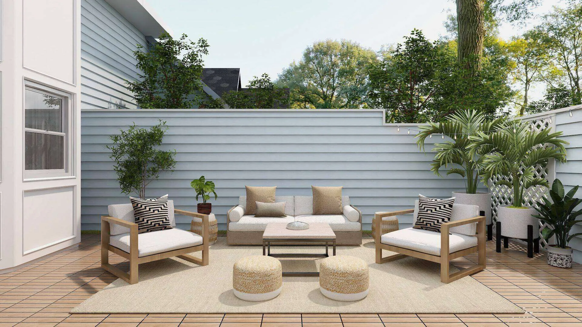 Outdoor deck with wooden flooring, seating, and potted plants against a white fence.