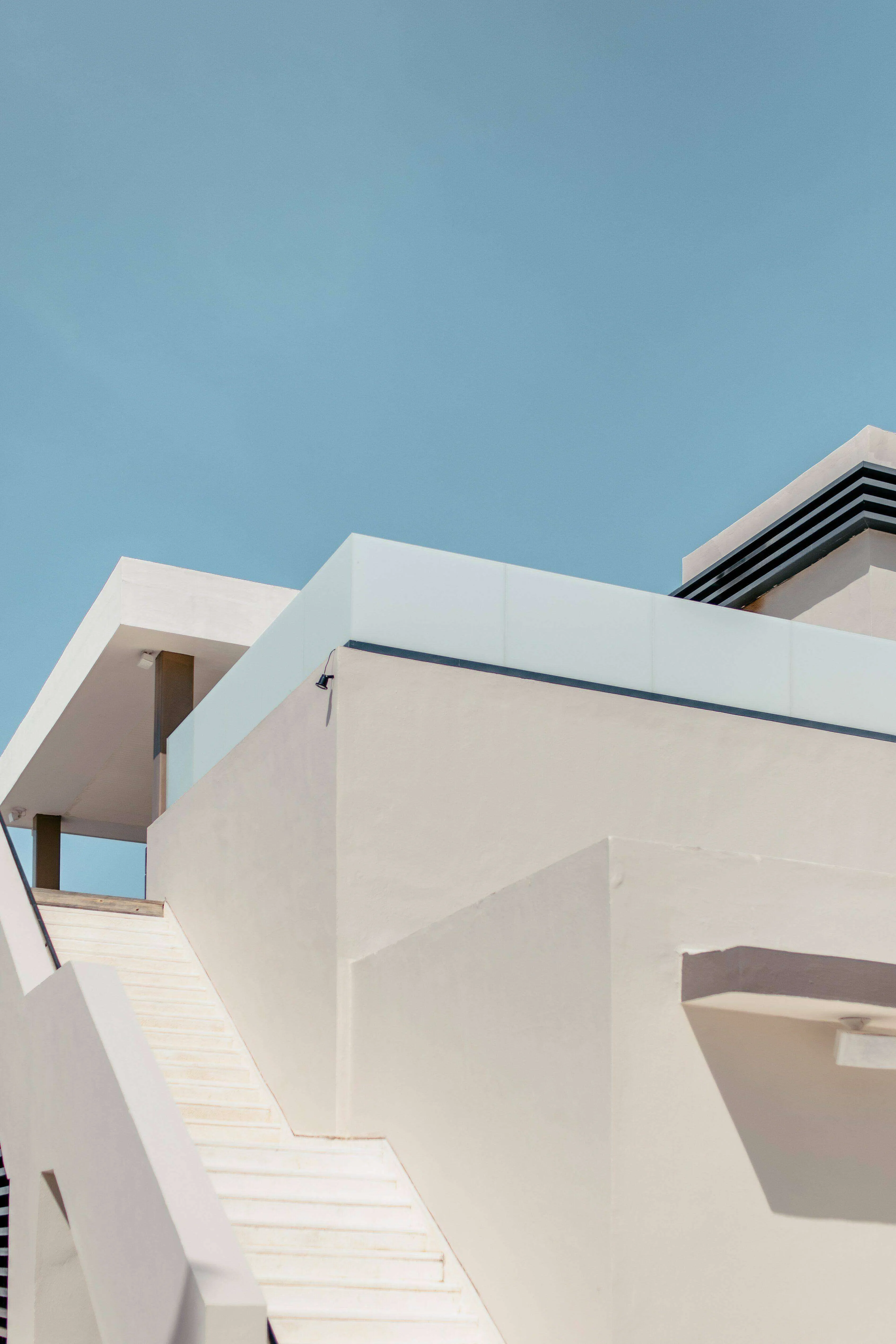 Modern building with smooth plastered walls and a staircase under a clear blue sky.