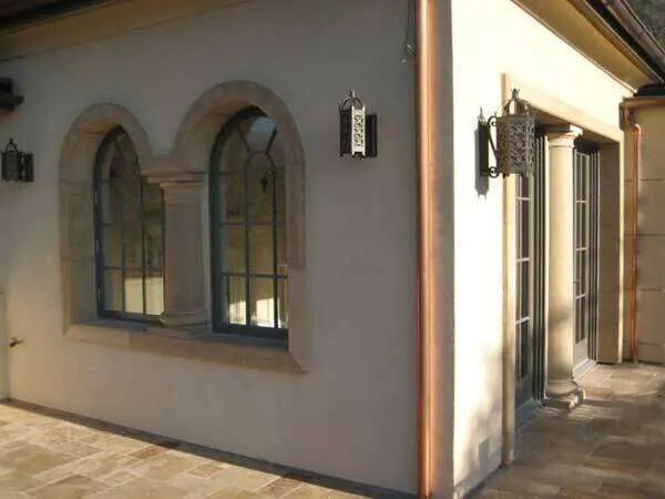 Building exterior with stucco walls, arched stone-framed windows, and decorative sconces. — St. Helena area