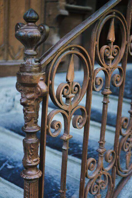 Close-up of an ornate metal staircase railing with intricate scrollwork.