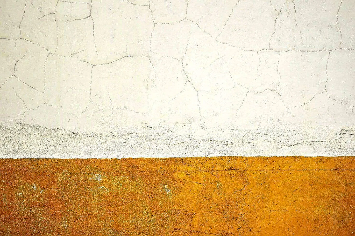 Wall with visible plaster cracks on white section and textured orange section below.