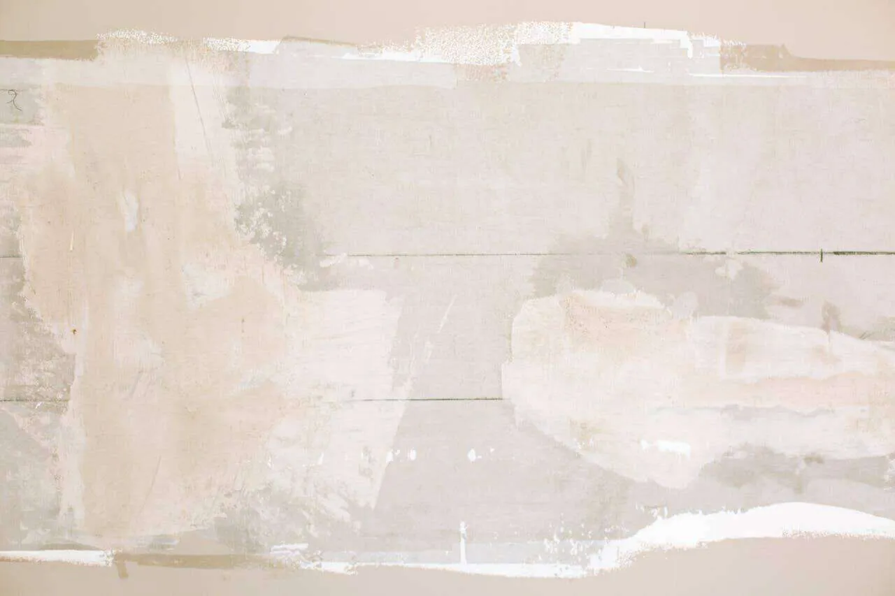Wall with visible plaster patches and repairs in beige and white tones.