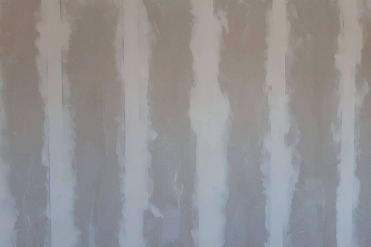 Plasterboard wall with seams filled with plaster filler in a residential interior setting.