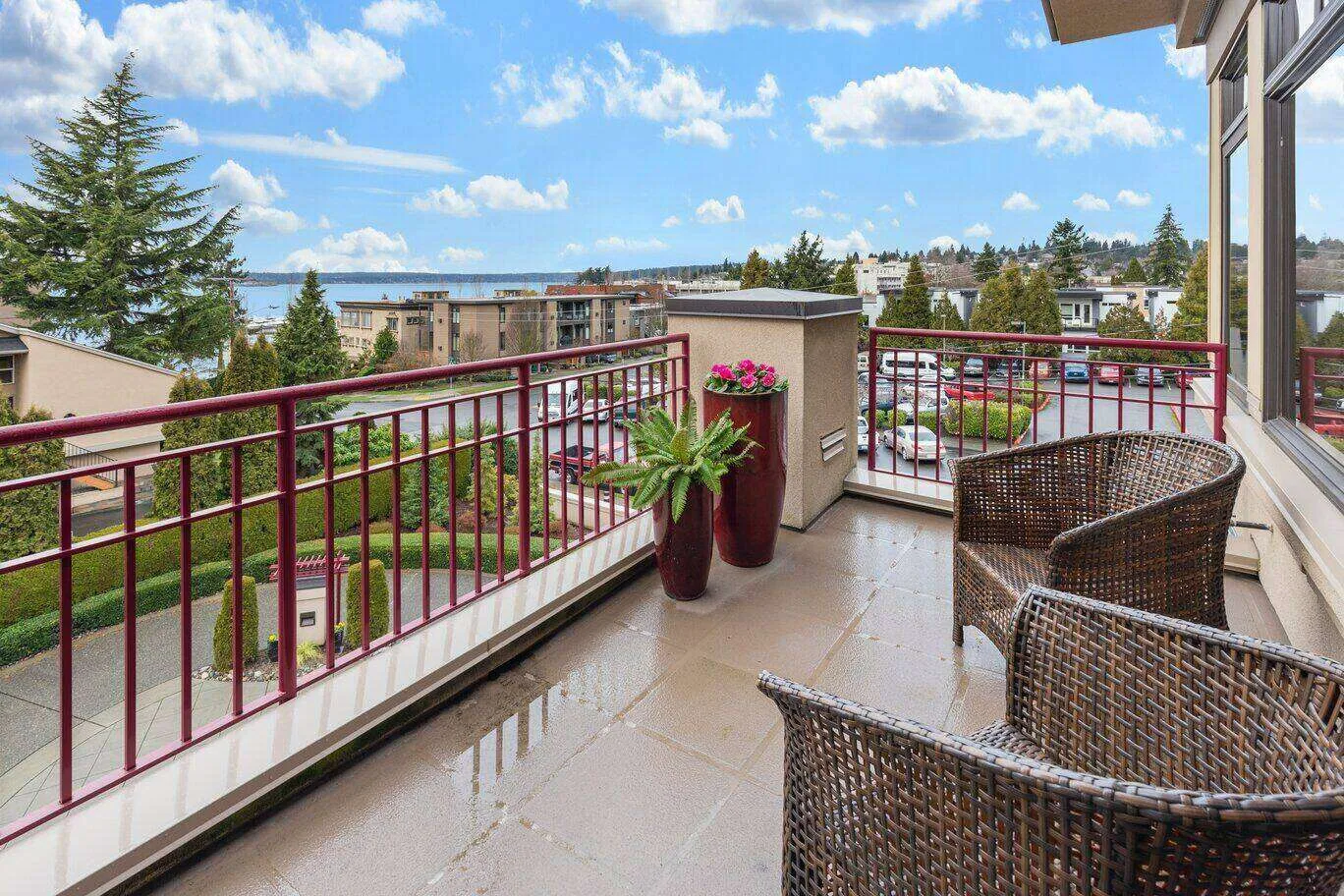 Balcony with wicker chairs and potted plants overlooking a suburban neighborhood. — Novato area