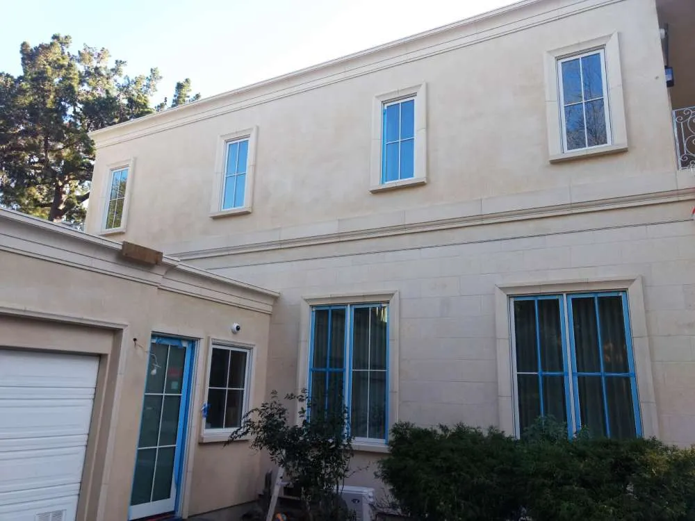 Two-story house with smooth stucco finish and blue-framed windows in Hillsborough. — Hillsborough area
