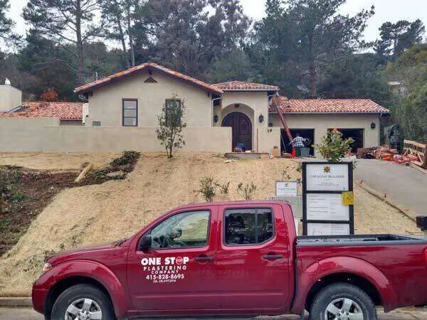 Residential home with stucco exterior and One Stop Plastering truck in front.
