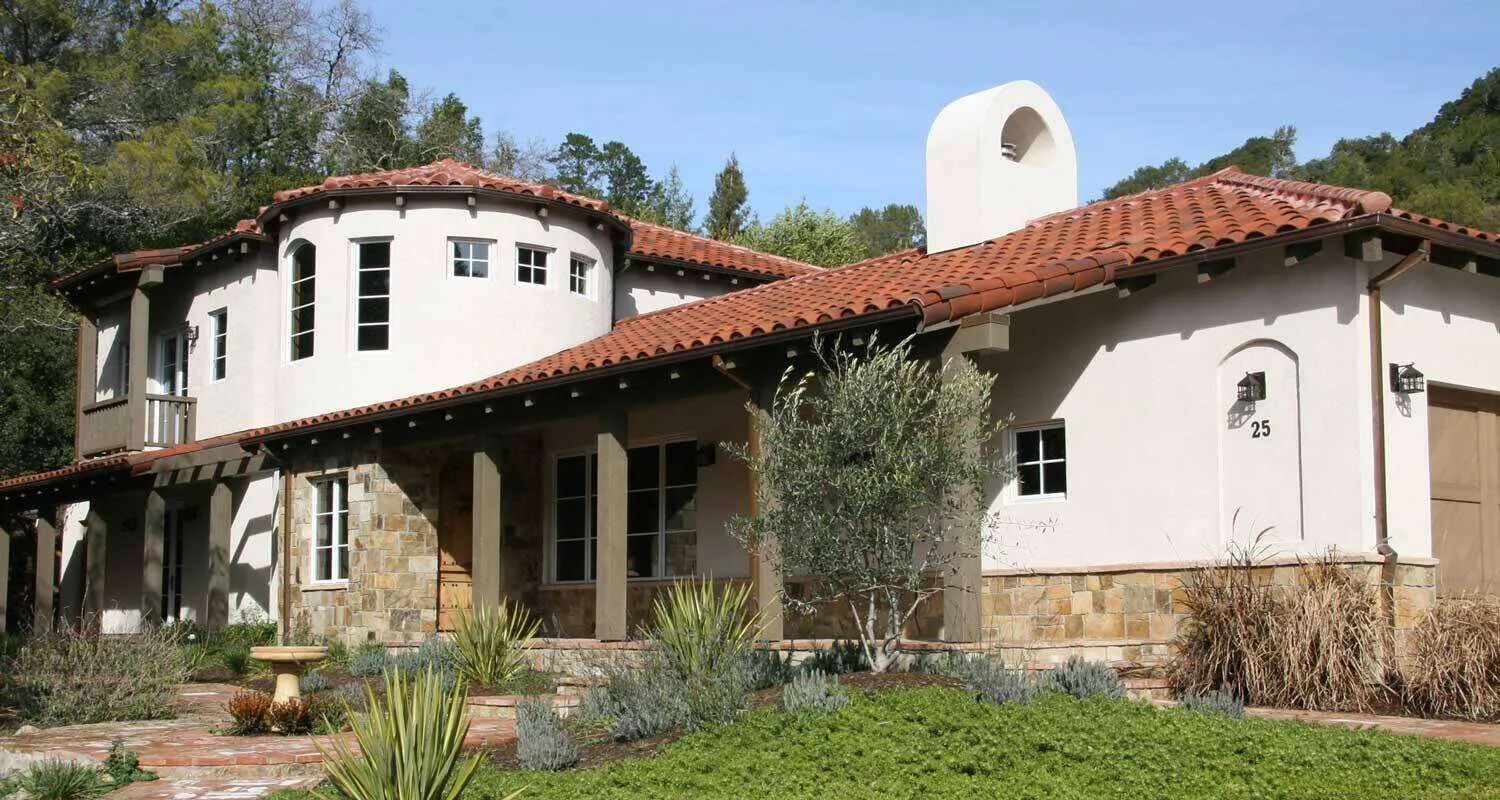 Mediterranean-style home with stucco walls, red tile roof, and arched windows in a landscaped setting. — Kentfield area