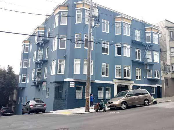 Multi-story blue stucco building with white windows on a sloped street in San Francisco. — Novato area