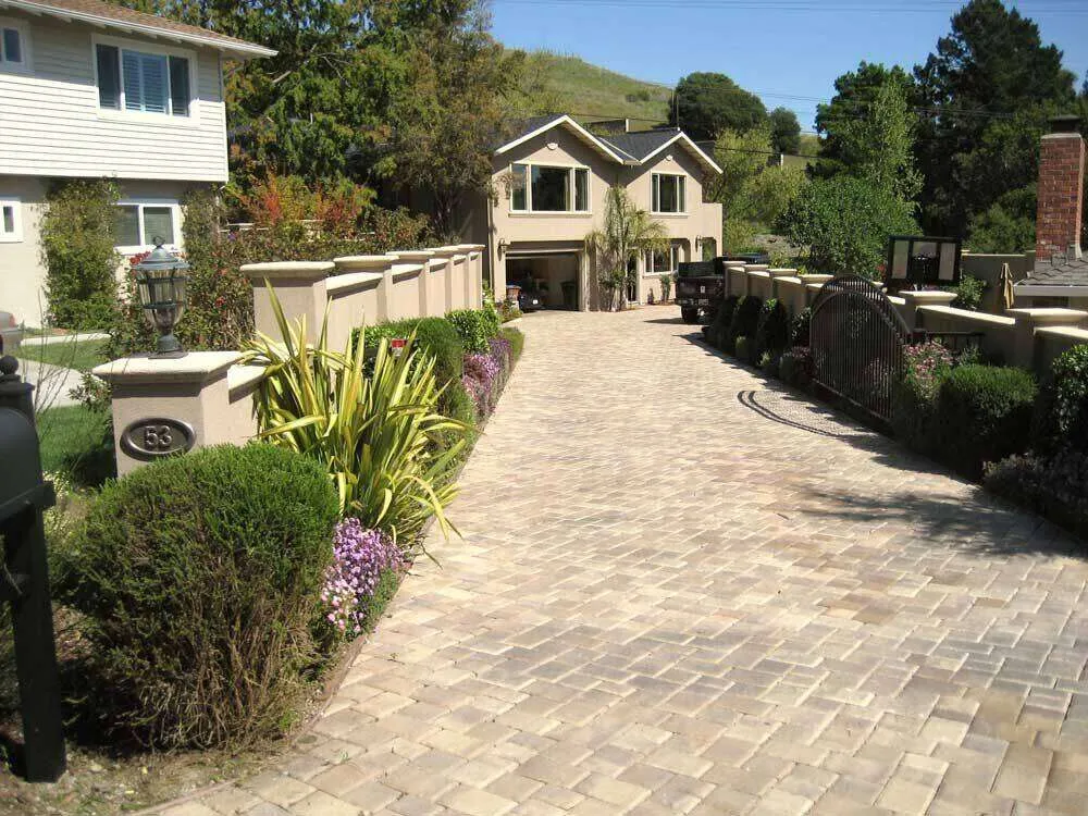 Stone driveway leading to a stucco house with a stucco fence and landscaping in San Rafael. — Larkspur area