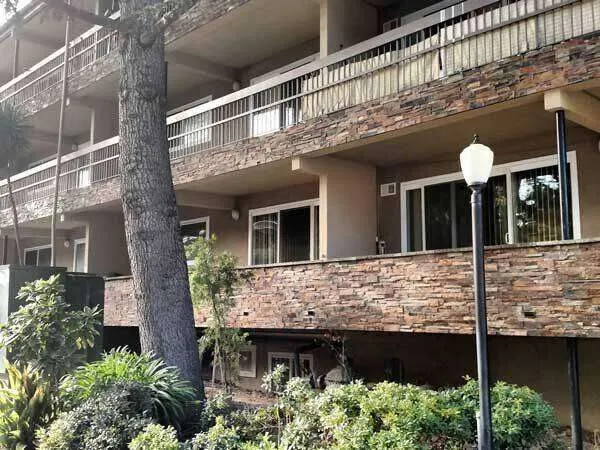 Multi-story building with stone railings and landscaped foreground.