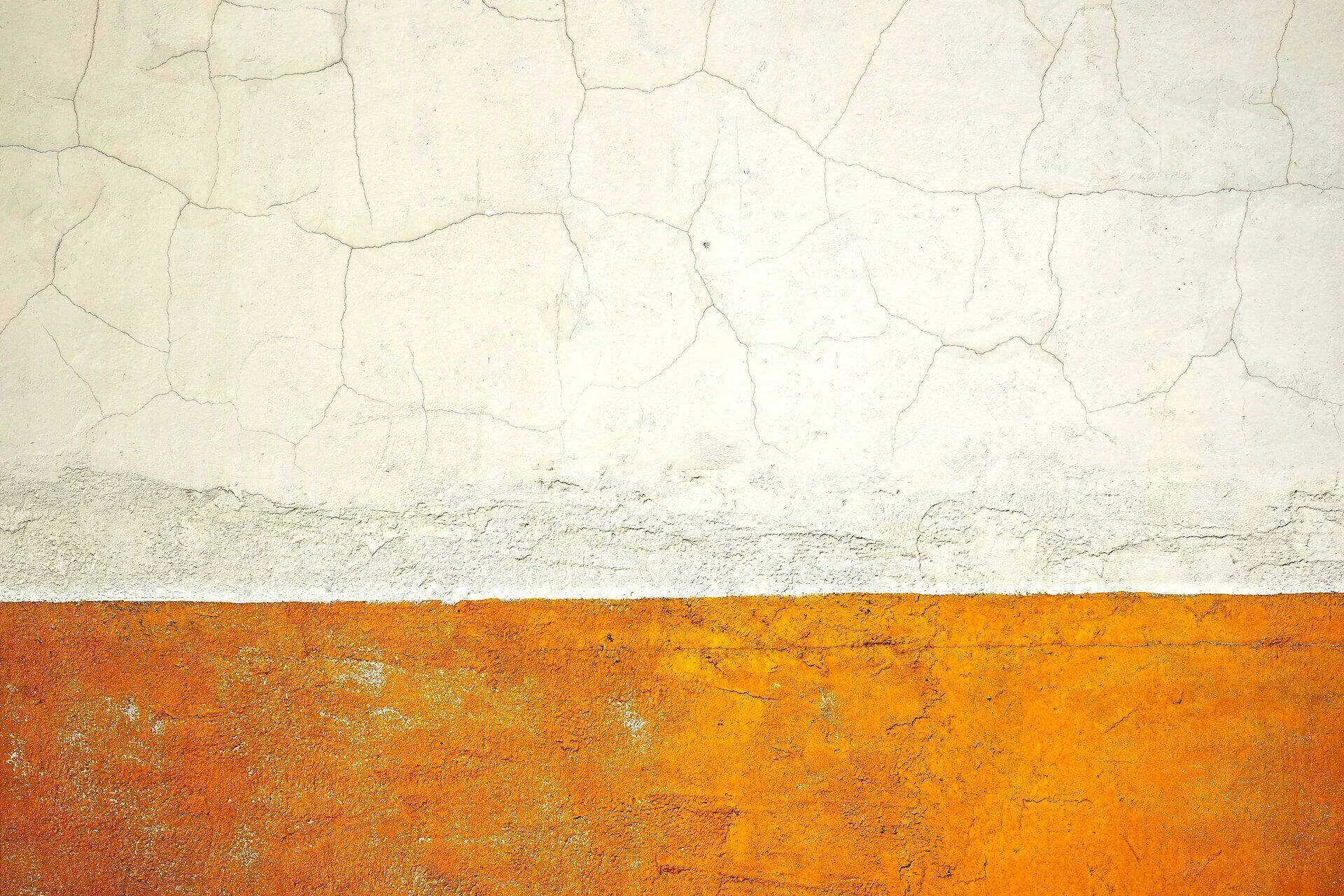 Wall with cracked white stucco above and textured orange stucco below. — Berkeley area
