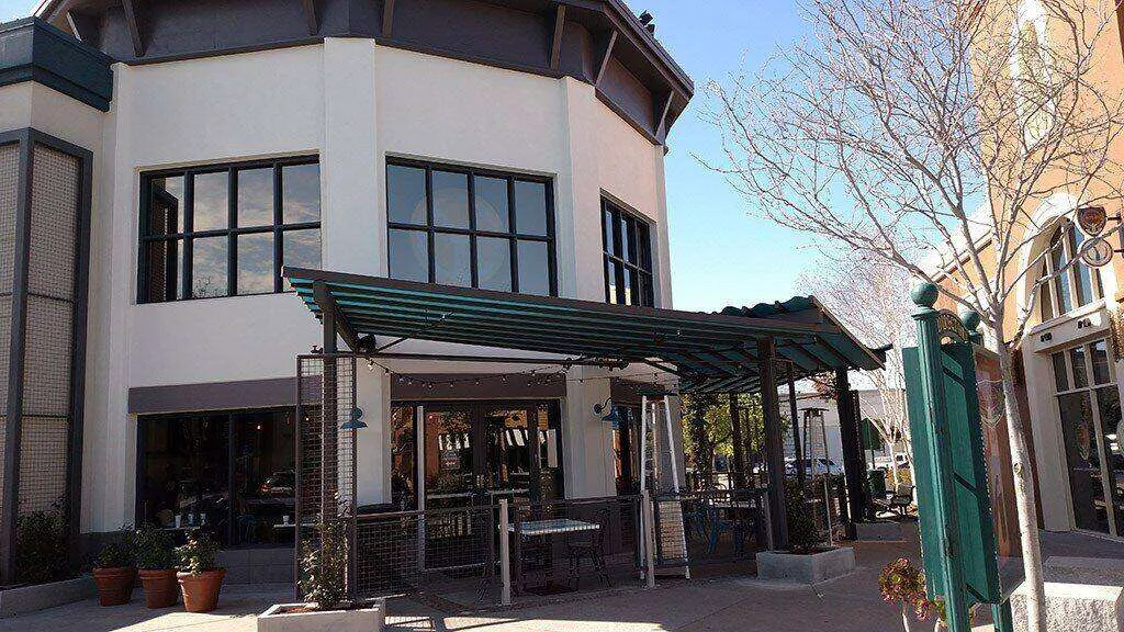 Commercial building with stucco exterior and outdoor seating at Corte Madera Shopping Center.