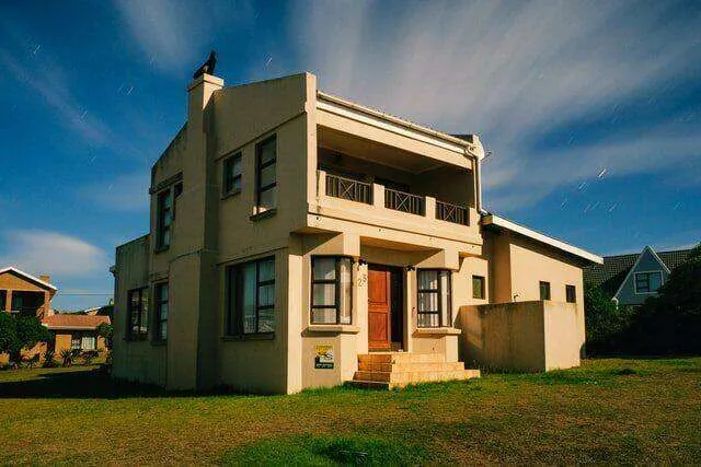 Two-story house with stucco exterior, front porch, and windows under a blue sky. — San Anselmo area