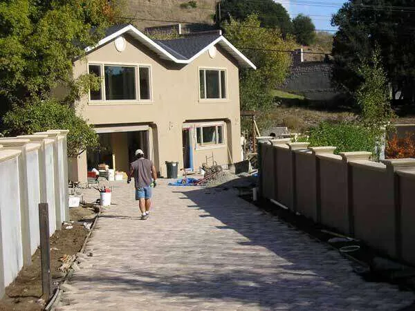 Two-story stucco home with paved driveway and construction materials around. — Greenbrae area